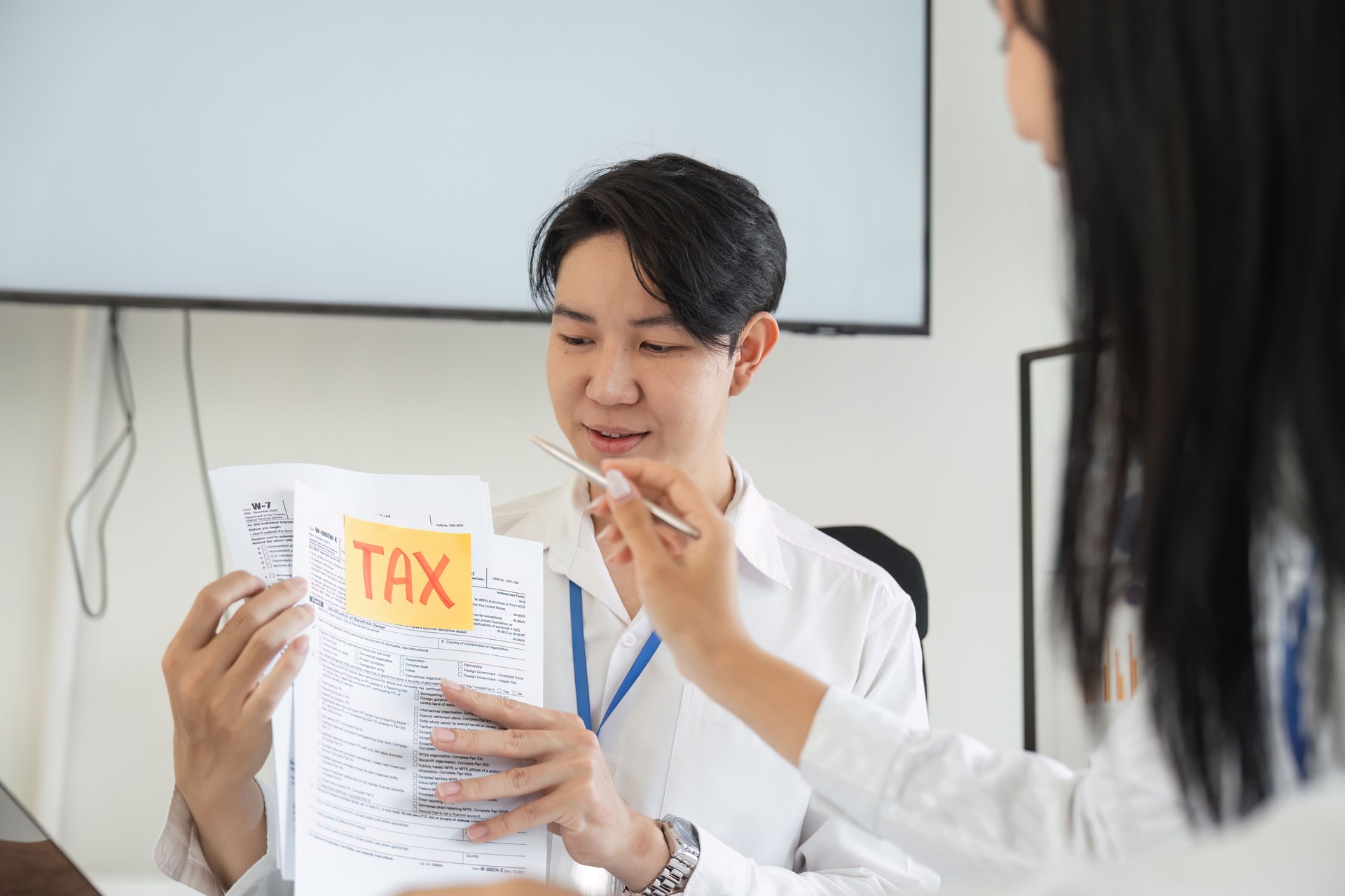 Tax consultant reviewing tax documents with a colleague in an office setting.