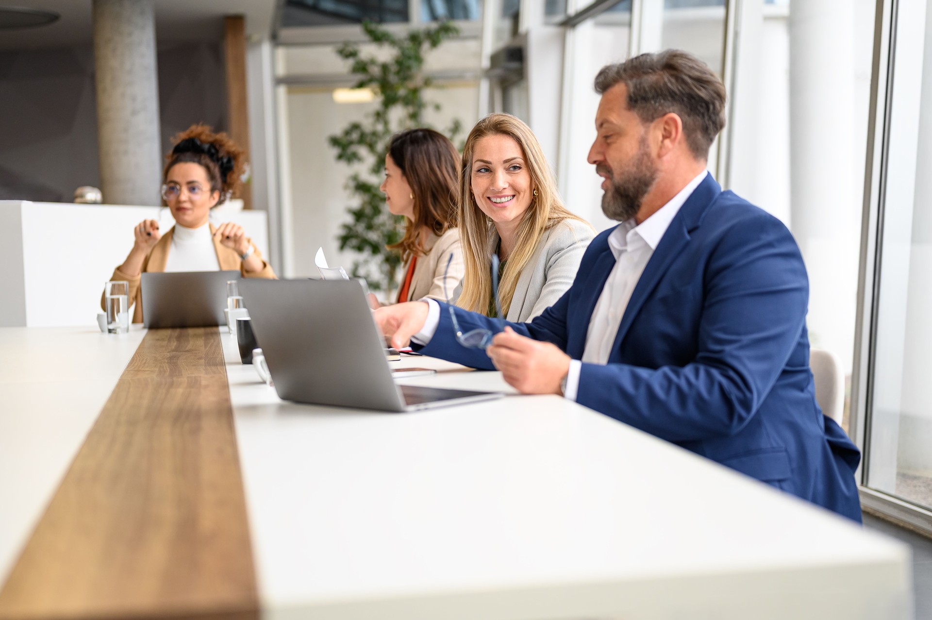 Businessman working on laptop and discussing ideas with female colleague during meeting in office